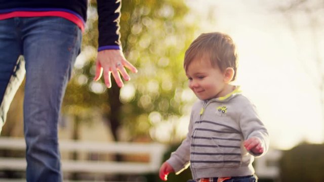Adorable little boy walking in a park and holding his mother's hand