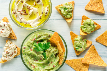 Bowls of hummus and guacamole with tortilla chips