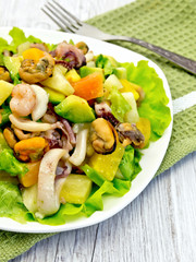 Salad with seafood and avocado in plate on  light board