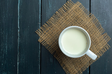 Glass of milk on table on blurred natural background