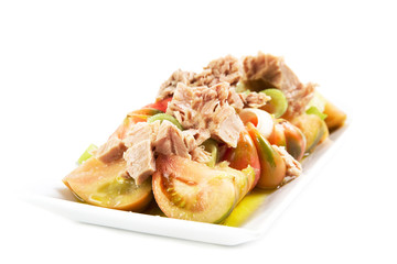 Ensalada de atún y tomate sobre un plato cuadrado sobre fondo blanco aislado. Vista de frente y superior