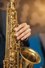 Musical instrument saxophone close-up. Hands on a musical instrument. Young guy playing jazz.