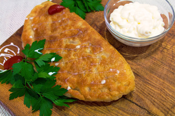 Baking golden meat with sauce and greens on a wooden board