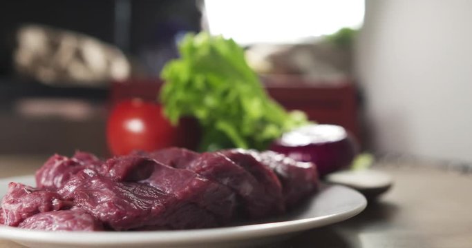 fresh raw beef slices on plate on kitchen table