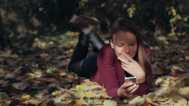portrait of pretty young women at autumn park looking at smart phone seeing bad news or photos with disgusting emotion on her face. Human emotion, reaction, expression.