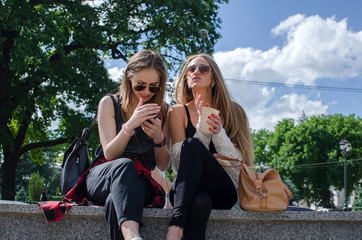 Two girlfriends are playing with the cellphone