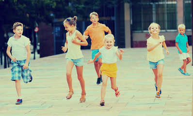 kids actively playing and running together on street on summer d