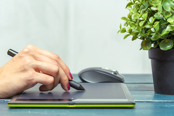 Hand of graphic designer working with stilus and tablet