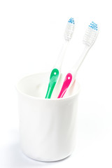Toothbrushes in glass on table on light background