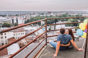 Fototapeta na wymiar Young couple exploring an old town. Man pointing at some landmark. Man and woman with baloonsvisiting city and enjoying view. building city administration currently open view point for tourists. 