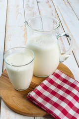 fresh milk in glass jug and glass on wooden background