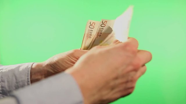 Close up of hands counting various european euro notes over green background.