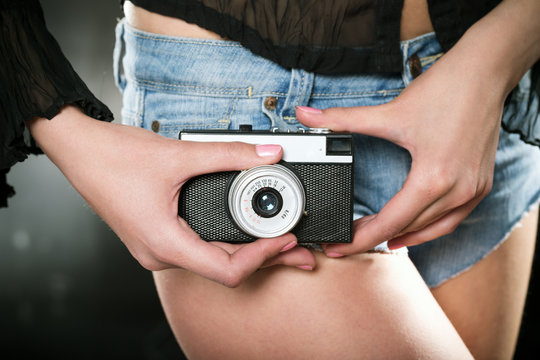 girl in shorts holding a vintage camera..