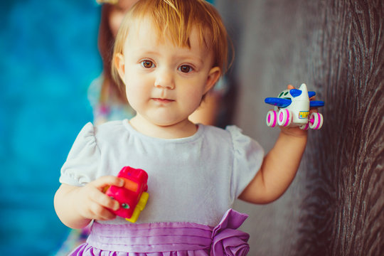 Little girl with deep hazel eyes holds in her tiny arms an airpl