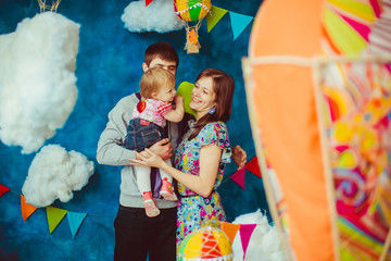 Smiling mom admires little daughter held by her husband