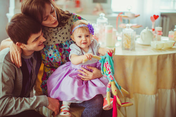 Fototapeta premium Girl in violet dress holds in her hands a toy rabbit while sitti