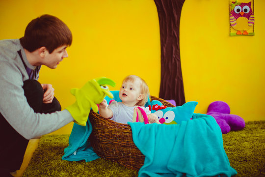 Dad tells a story for his little daughter while they play toys