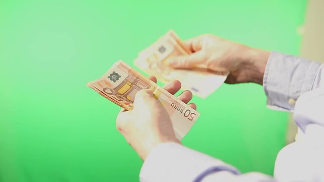 Close up of a pair of hangs counting euro banknotes. Filmed behind an isolated green screen