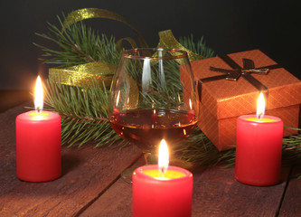 Christmas Composition with glass cognac, Gift box and candle on wooden table