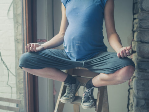 Pregnant woman meditating on ladder