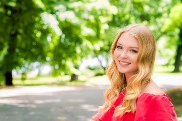 Young smiling blonde woman outdoors portrait. Soft sunny colors.Close portrait.