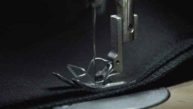 A sewing machine in motion. Close-up of sewing machine needle rapidly moves up and down. Close-up of sewing machine parts. Foot needle. Needle plate. Sewing. Create a line. Sewing needle.