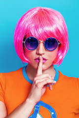 Woman pop portrait wearing pink wig and making silence gesture