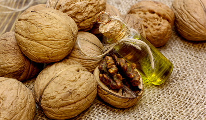Natural organic cosmetic SPA concept. Vintage bottle walnut oil, autumn flower, and open nuts core on coarse cloth sacking