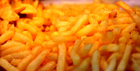 Large pan of fresh cooked sweet potato fries, fresh out of frying oil yellow colorful close up patterns