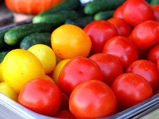 Heap of whole natural tomatoes and cucumbers. Sale on small market.