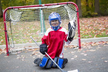 boy dressed to be the goalie in a street hockey game