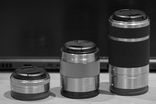 Fototapeta closeup macro of three camera lenses in a row ascending by size low key black and white image