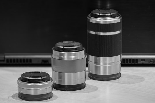 Fototapeta closeup macro of three camera lenses in a row ascending by size low key black and white image