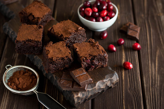 Dark chocolate brownies with cranberries on rustic wooden background