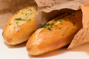 two baguettes covered with greens potherbs herbs in paper bags closeup shot