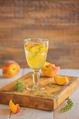 Lemonade with peaches and thyme in a glass, selective focus