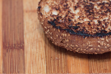 closeup shot of fried toasted roasted hamburger burger roll on a cutting board
