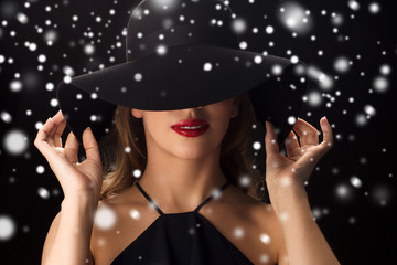 beautiful woman in black hat over snow