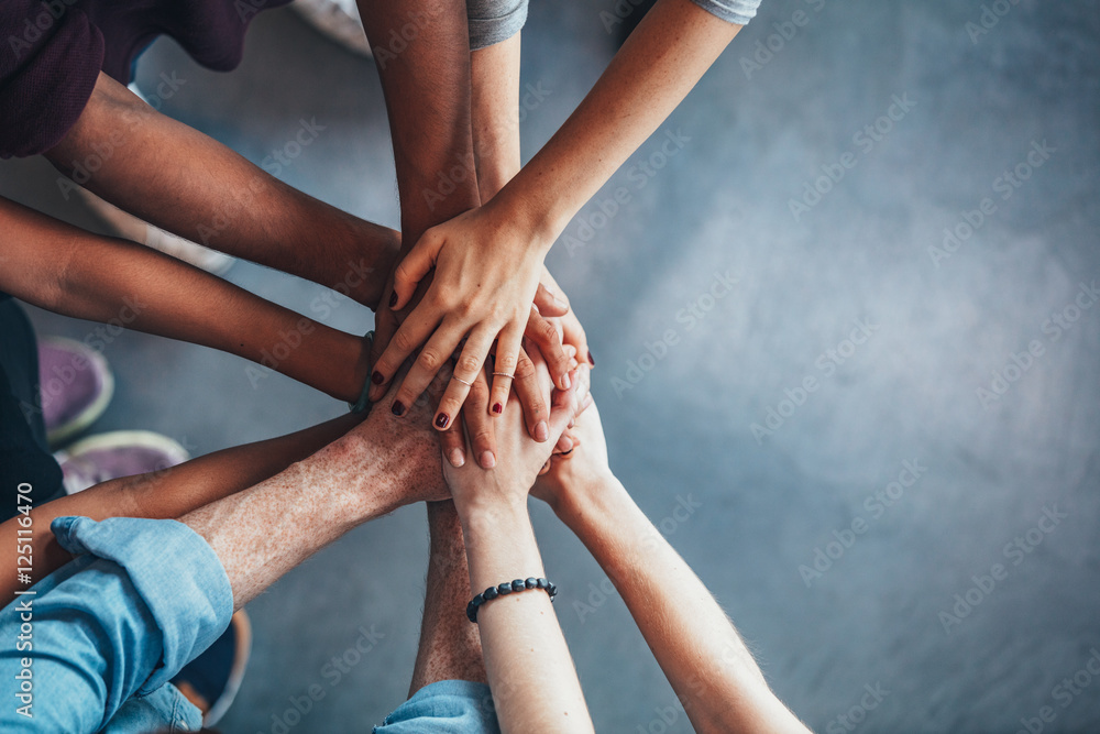 Fototapete stack of hands showing unity and teamwork