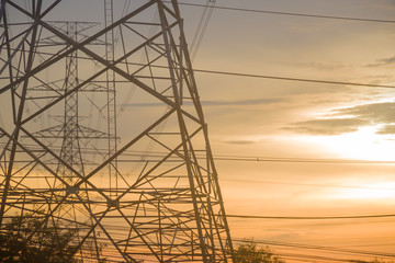 Electricity pylon silhouetted against blue sky wih cloud background. High voltage tower