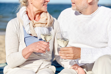 happy senior couple drinking wine on summer beach