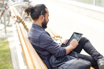 Fototapeta premium man with tablet pc sitting on city street bench