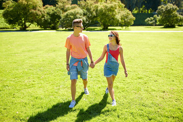 Naklejka premium happy teenage couple walking at summer park