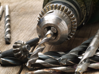 used drill machine chuck and assorted drill bits closeup, shallow depth of field, focus on chuck
