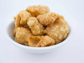 Crispy deep fried pork skin or pork rind in bowl isolated on white background