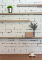 White brick wall and shelf with the foreground of wooden table, small plants and lavender