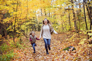 Fototapeta premium Young mother playing with her daughter in autumn park