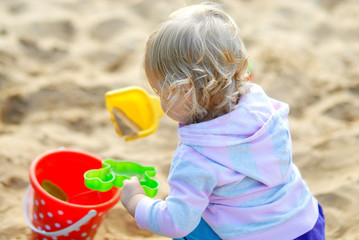 Happy child playing with sand in summer