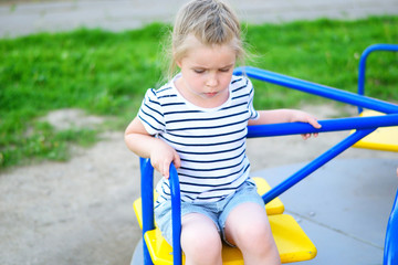 Adorable sad little girl on carousel