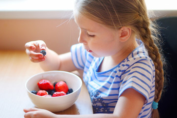 Adorable girl eating fresh berries